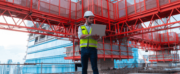 Engineer-using-laptop-in-front-of-building-construction-site